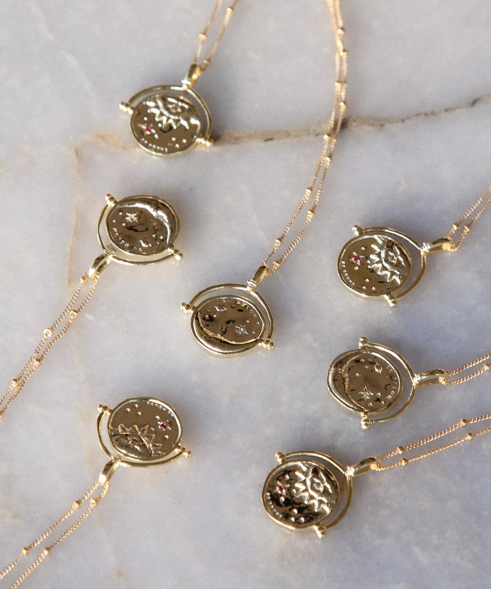 Gold Manifesting As Above So Below Spinner Necklace on marble.