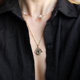 Gold Manifesting As Above So Below Spinner Necklace worn by woman with pearl necklace.