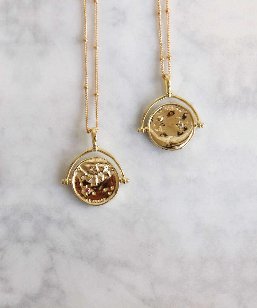 Gold Manifesting As Above So Below Spinner Necklace on marble.