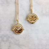 Gold Manifesting As Above So Below Spinner Necklace on marble.