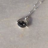 Sterling Silver Manifesting As Above So Below Spinner Necklace resting on marble.