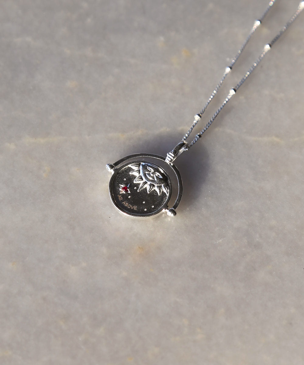 Sterling Silver Manifesting As Above So Below Spinner Necklace resting on marble.