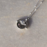 Sterling Silver Manifesting As Above So Below Spinner Necklace resting on marble.