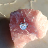 Sterling Silver Manifesting As Above So Below Spinner Necklace resting on rose quartz crystal stone.