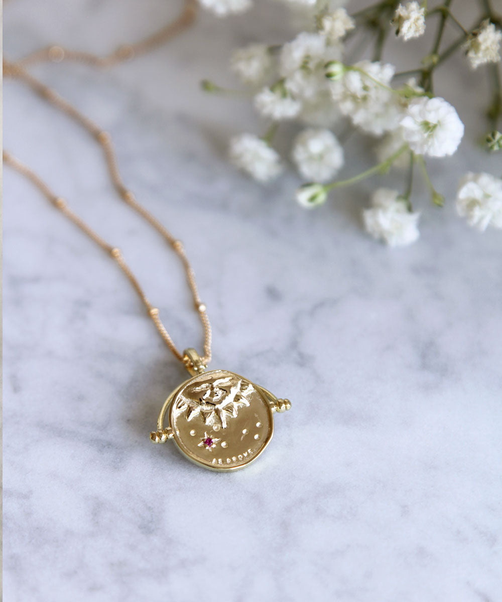 Gold Manifesting As Above So Below Spinner Necklace on marble.