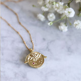 Gold Manifesting As Above So Below Spinner Necklace on marble.