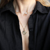 Gold Manifesting As Above So Below Spinner Necklace worn by woman with pearl necklace.