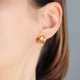 Vintage style gold earrings worn by woman.