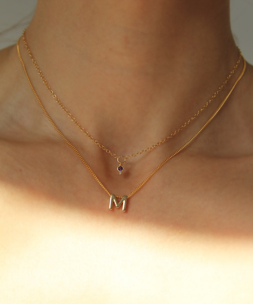 M Initial charm necklace stacked with February Amethyst mini birthstone necklace.