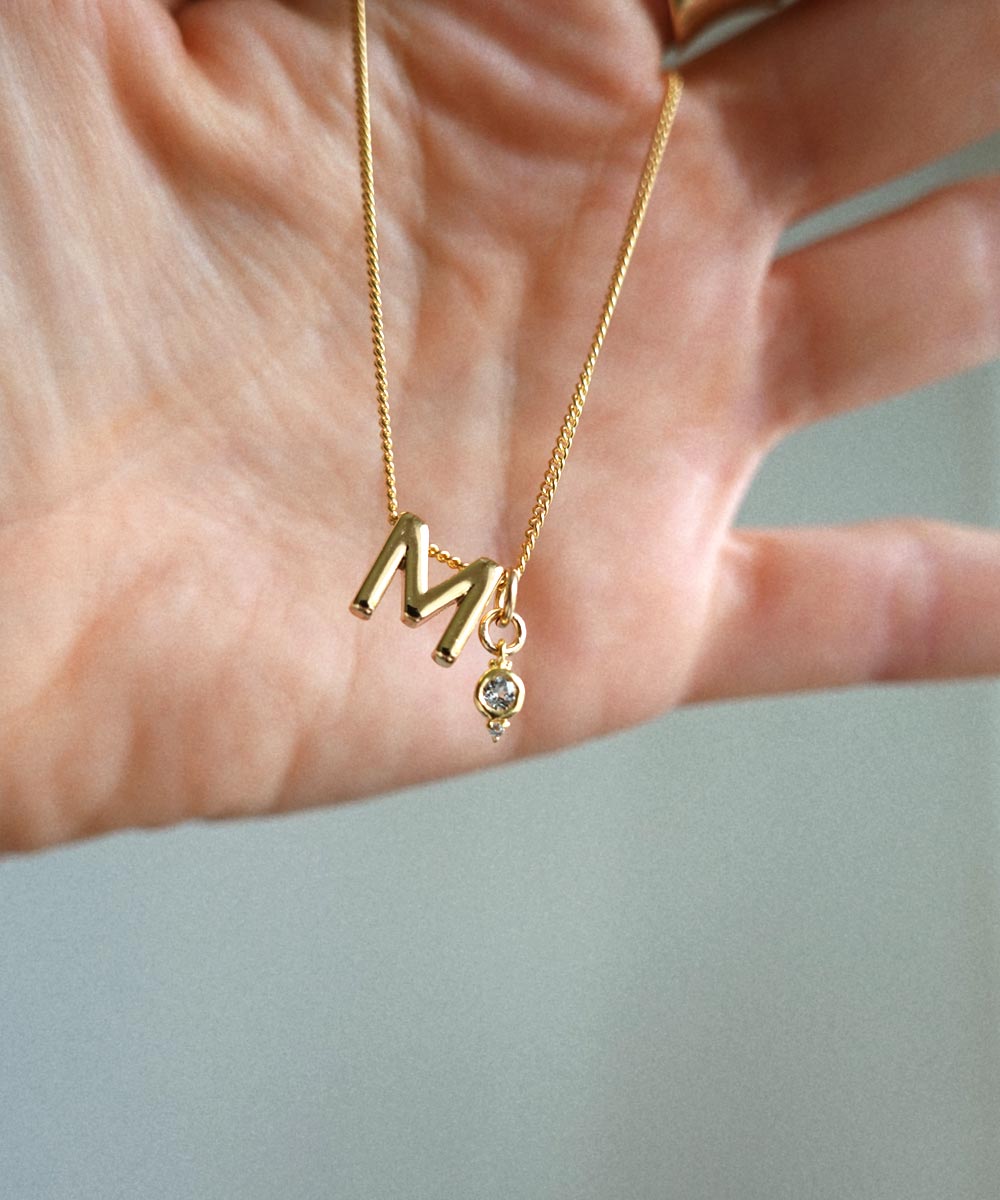 M Initial and April Birthstone Charm held by hand.