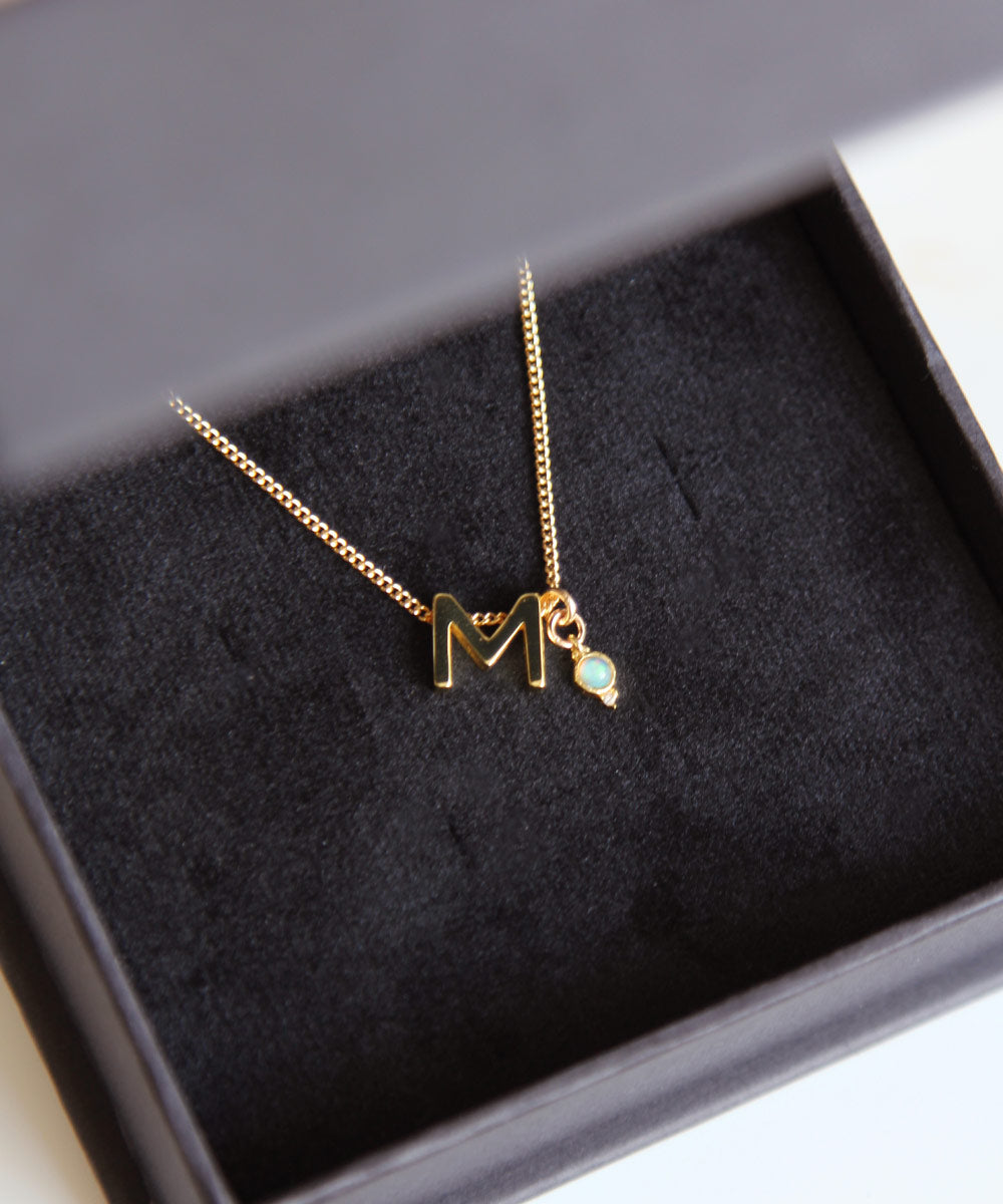 M Initial and Opal Birthstone Charm Necklace in black box.