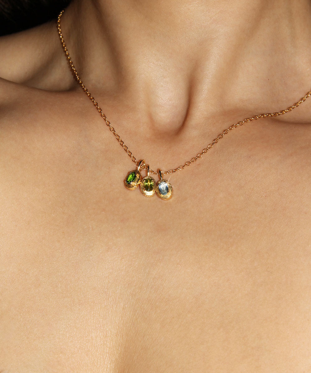 Maison de Femmes gold vermeil May Emerald, August Peridot and March Aquamarine Birthstone Necklace worn by woman.