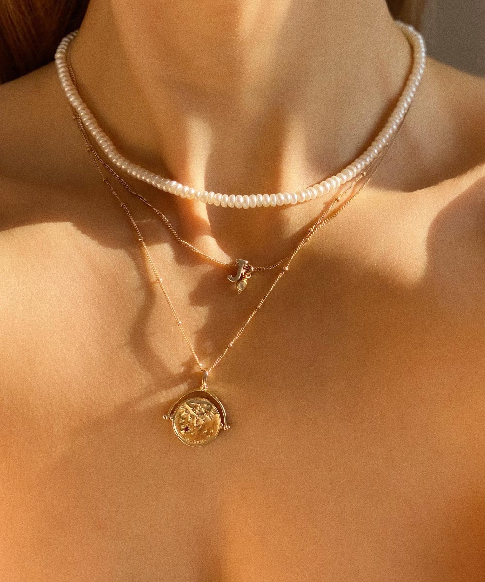 Gold Manifesting As Above So Below Spinner Necklace worn by woman with a J Initial + Birthstone Charm Necklace.