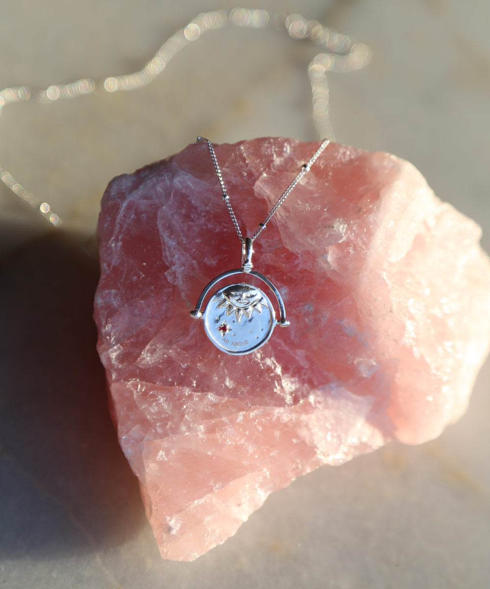 Sterling Silver Manifesting As Above So Below Spinner Necklace resting on rose quartz crystal stone.