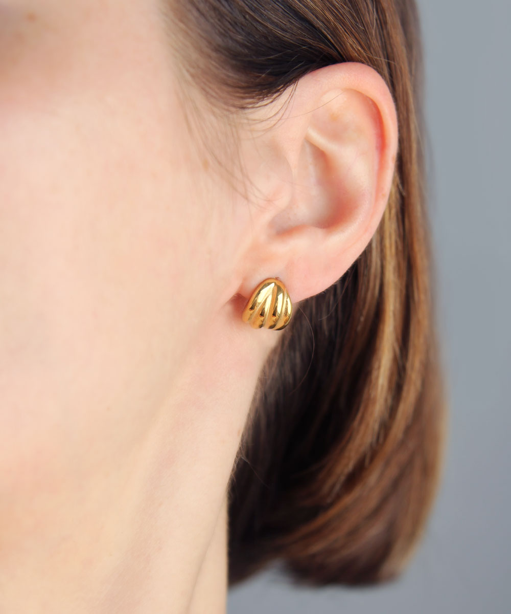 Vintage style gold earrings worn by woman.