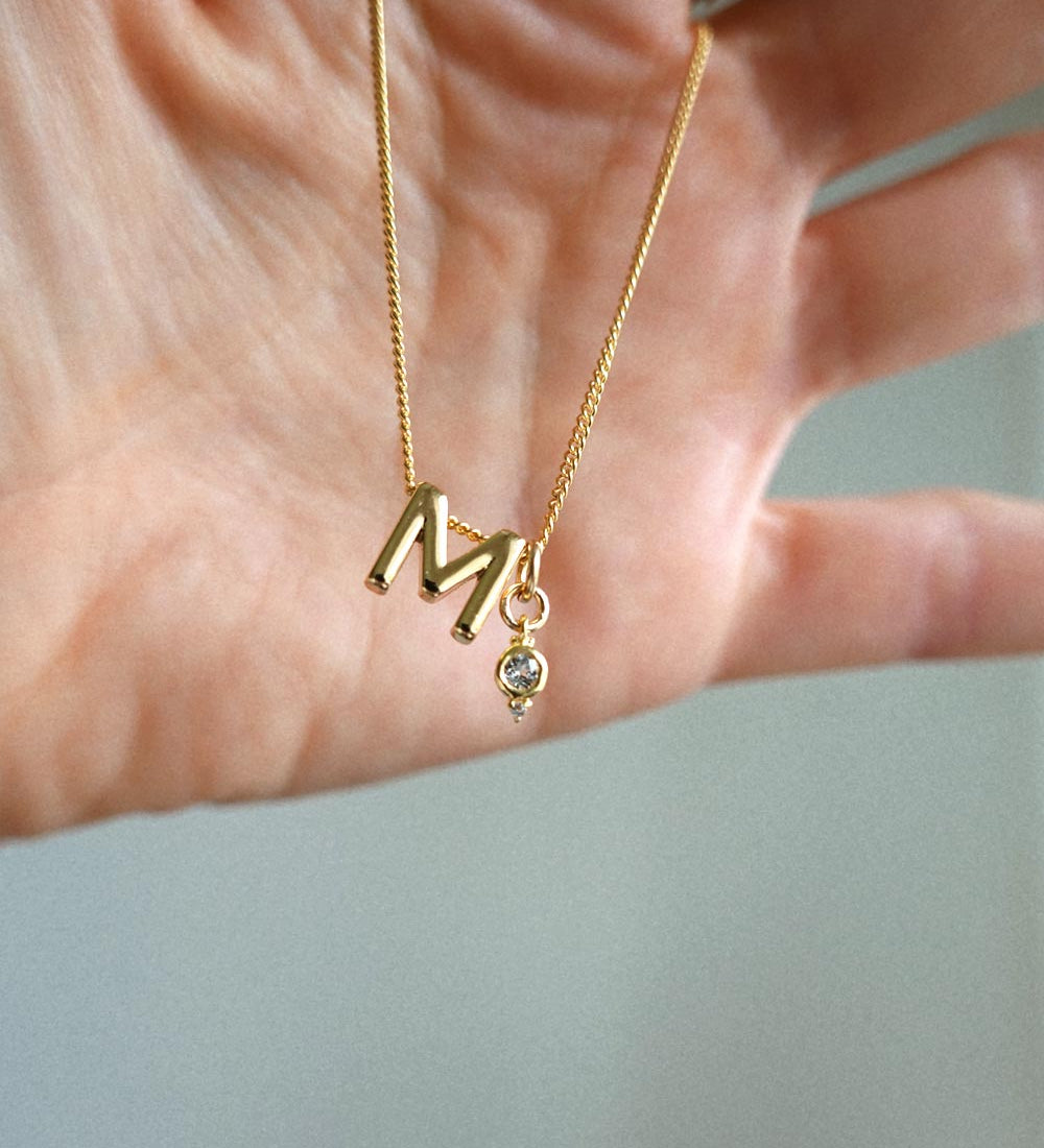 M Initial and April Birthstone Charm held by hand.