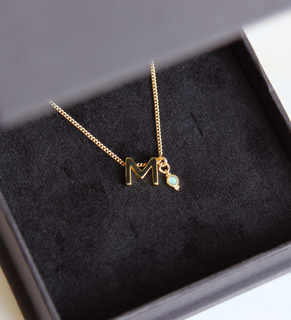 M Initial and Opal Birthstone Charm Necklace in black box.